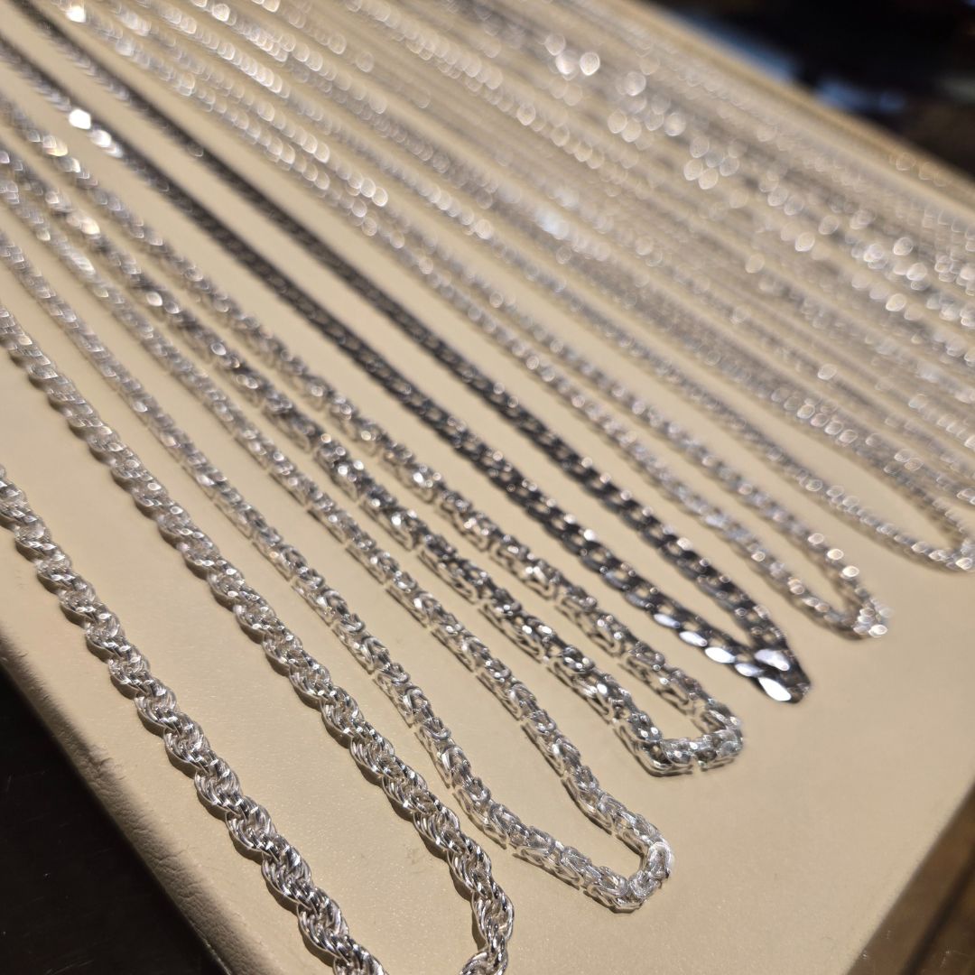 silver chains of different lengths on white background. meant to be bracelets.